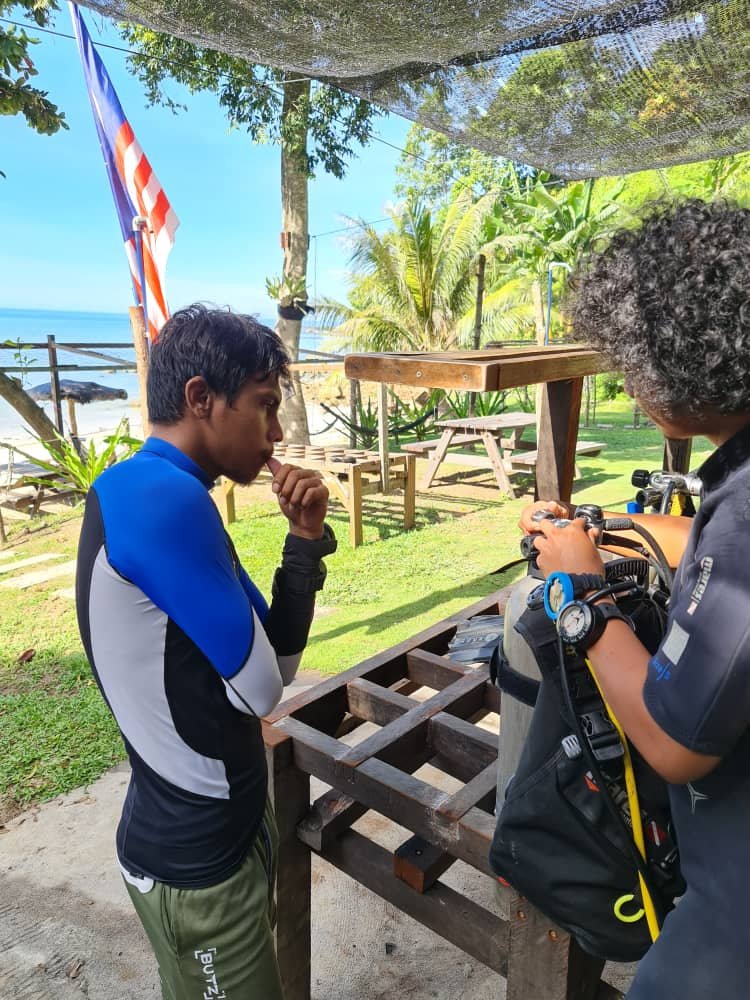 Dive instructor teaching newPADI  Open water course students how to set up dive equipment properly
