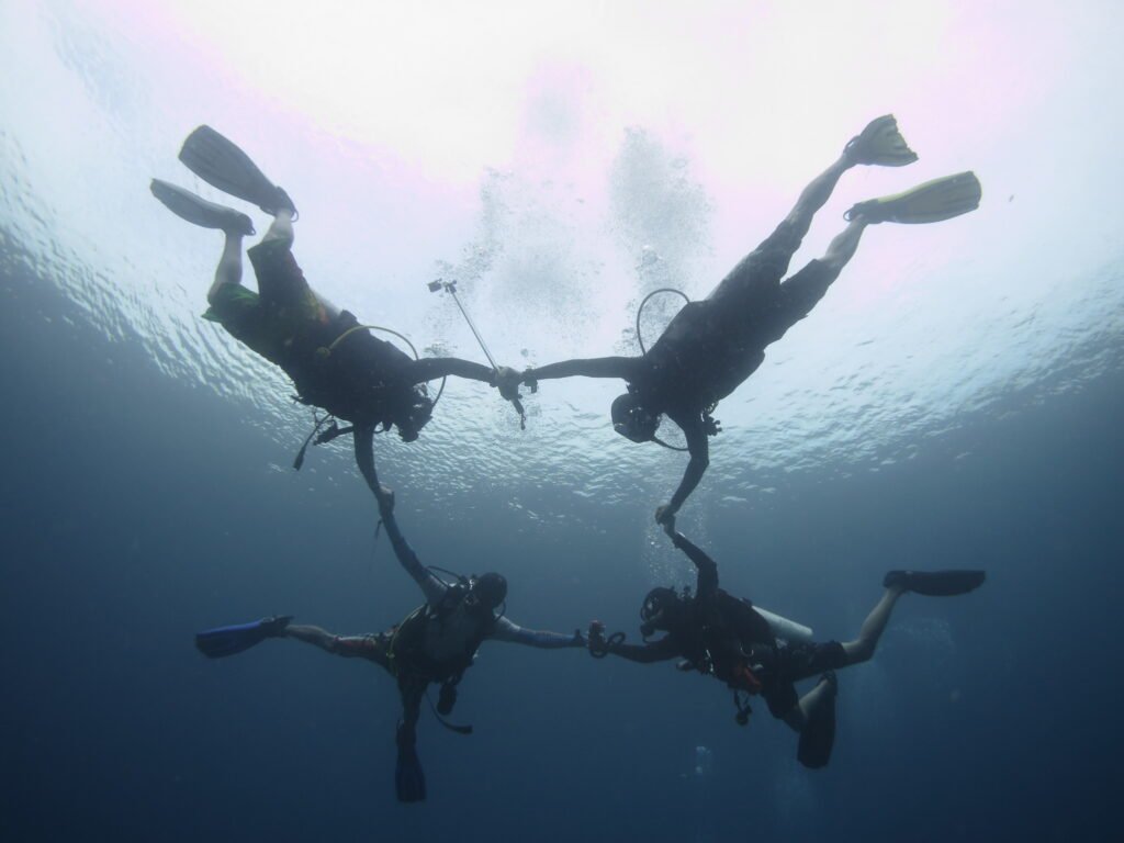 Four scuba divers holding hands underwater whilst conducting Advanced course training