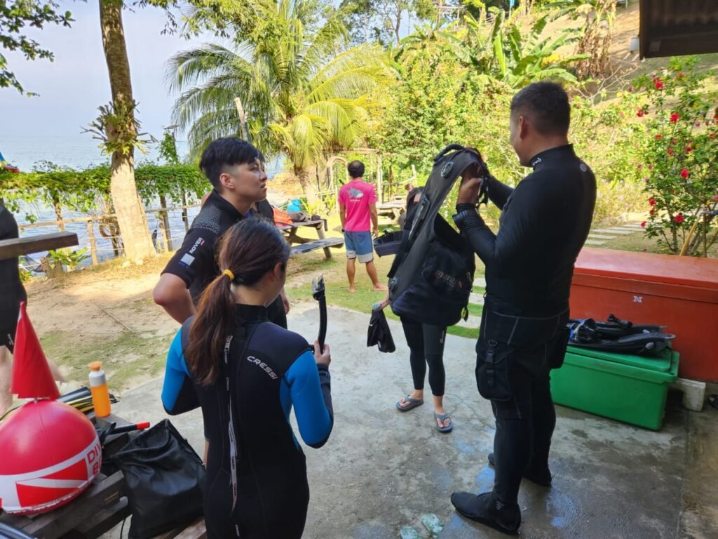 Dive instructor teaching new PADI Open water diver course students how to wash dive equipment properly