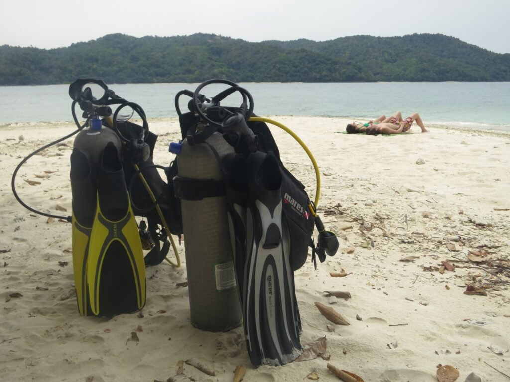 Scuba equipment and divers relaxing on the beach at Pandan Island Kota Belud Sabah